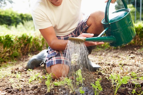 Operatives trimming a hedge in Upminster with green waste bags nearby